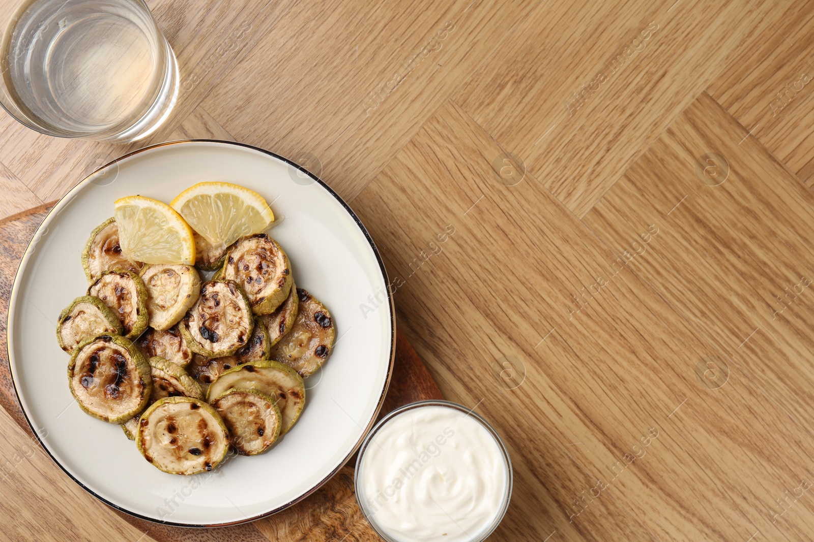 Photo of Tasty grilled courgette slices served on wooden table, flat lay. Space for text