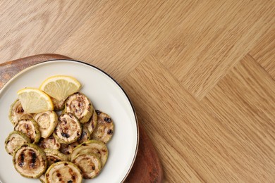 Photo of Tasty grilled courgette slices with lemon on wooden table, top view. Space for text