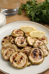 Photo of Tasty grilled courgette slices with lemon on table