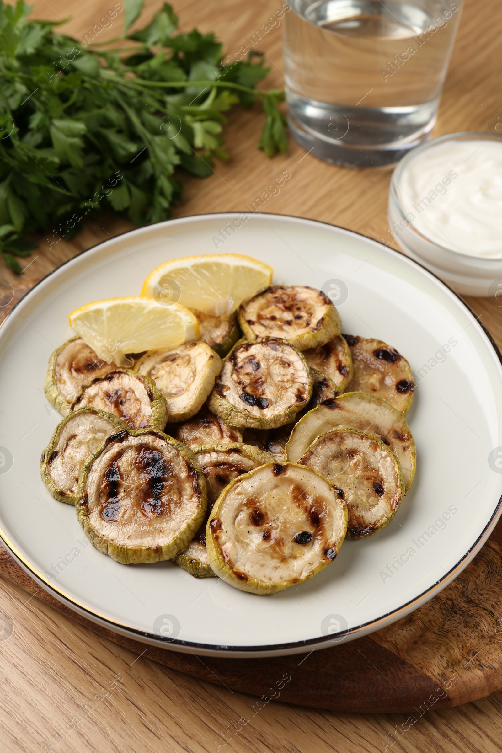 Photo of Tasty grilled courgette slices with lemon on wooden table