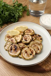 Photo of Tasty grilled courgette slices with lemon on wooden table