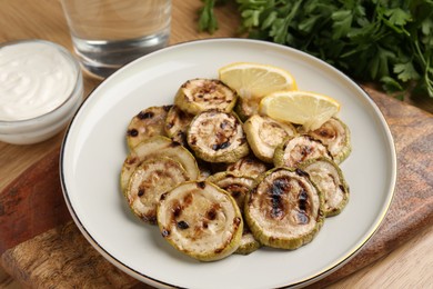 Photo of Tasty grilled courgette slices served on wooden table