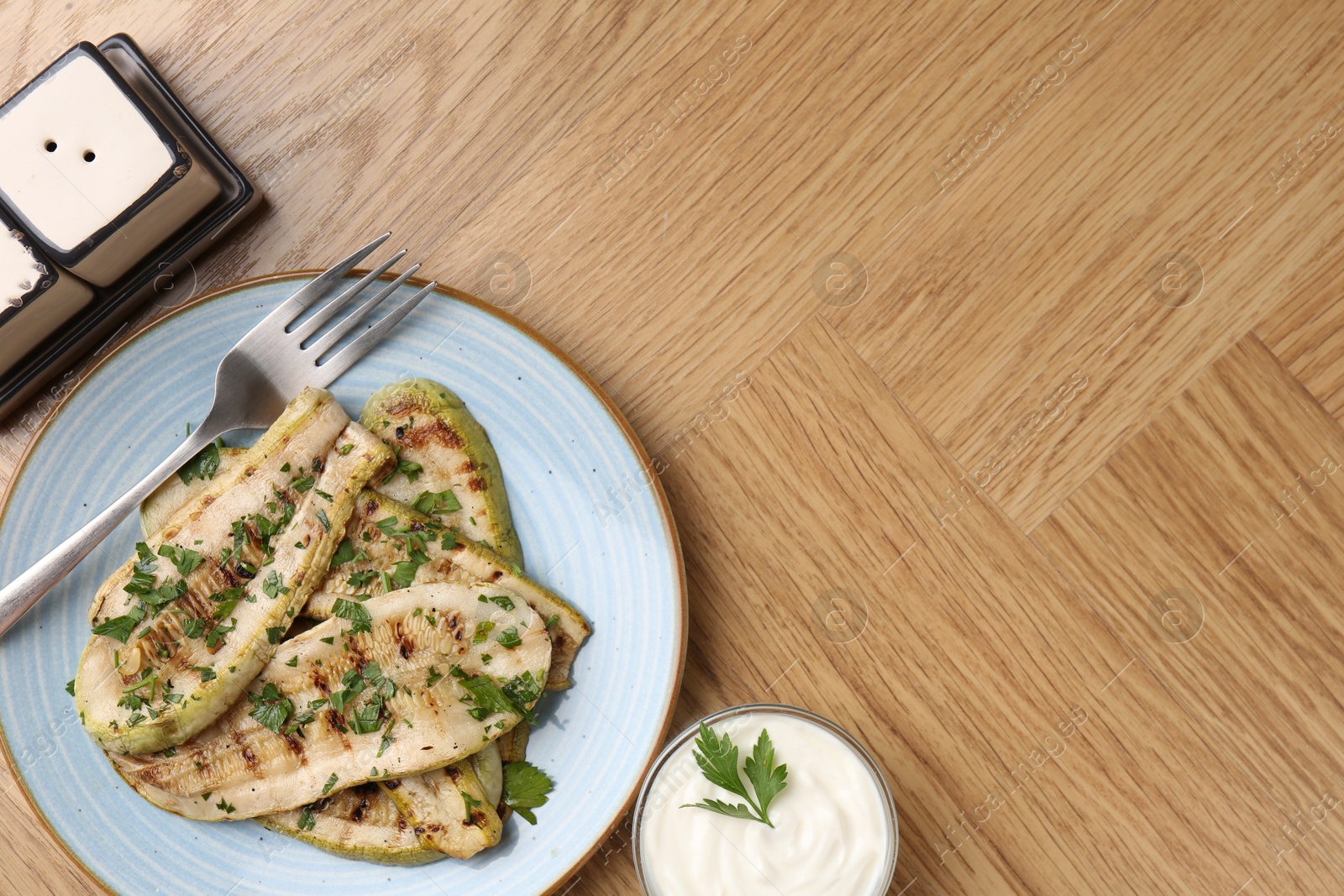 Photo of Tasty grilled courgette slices served on wooden table, flat lay. Space for text