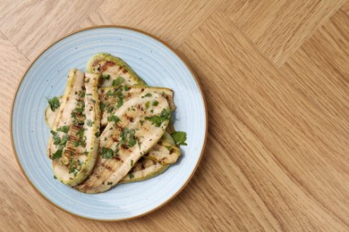 Photo of Tasty grilled courgette slices with parsley on wooden table, top view. Space for text