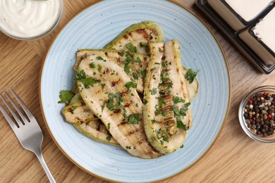 Photo of Tasty grilled courgette slices served on wooden table, flat lay