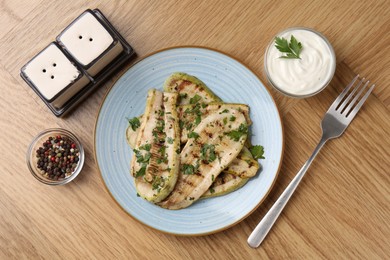 Photo of Tasty grilled courgette slices served on wooden table, flat lay