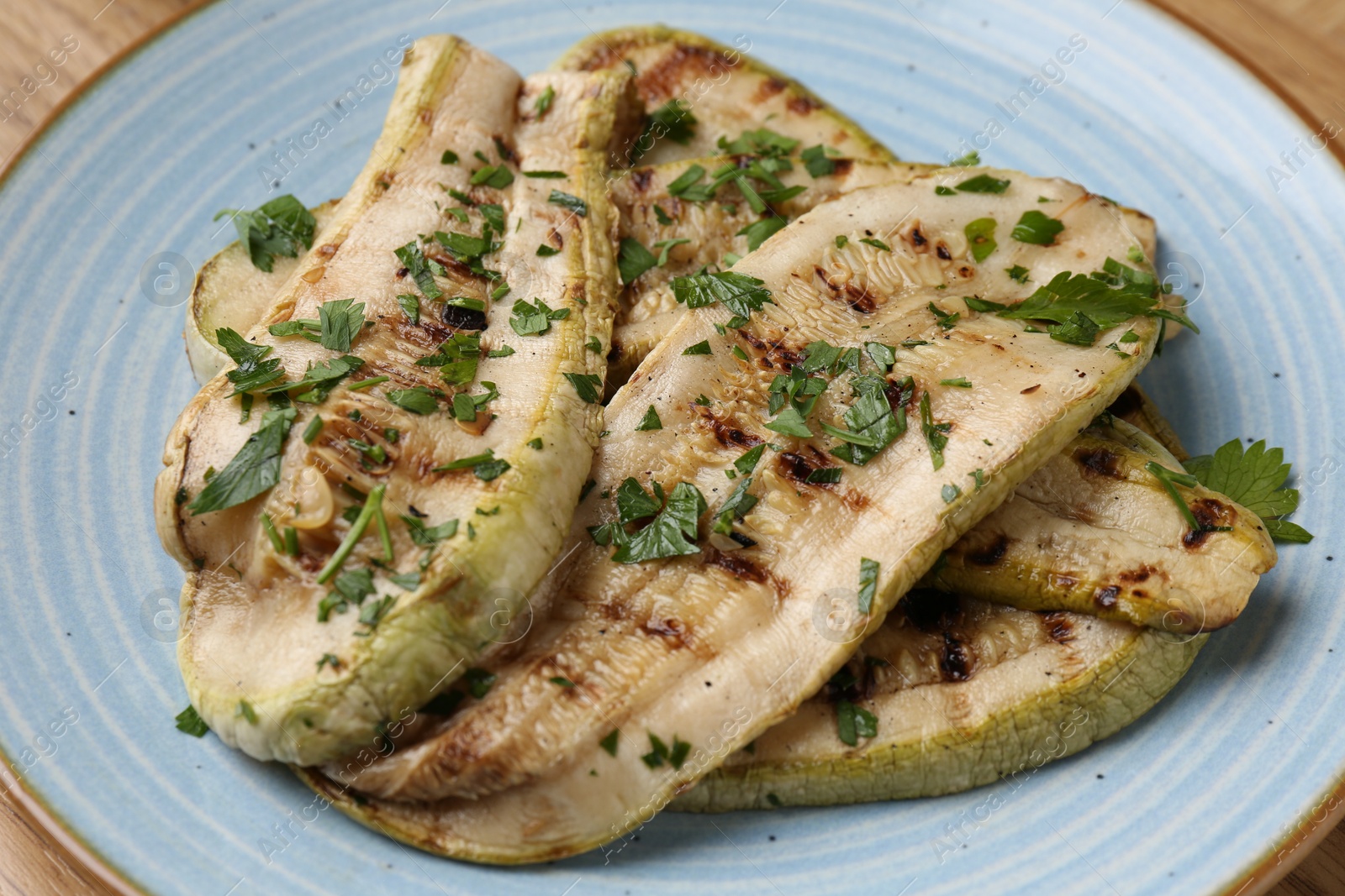 Photo of Tasty grilled courgette slices with parsley on table, closeup