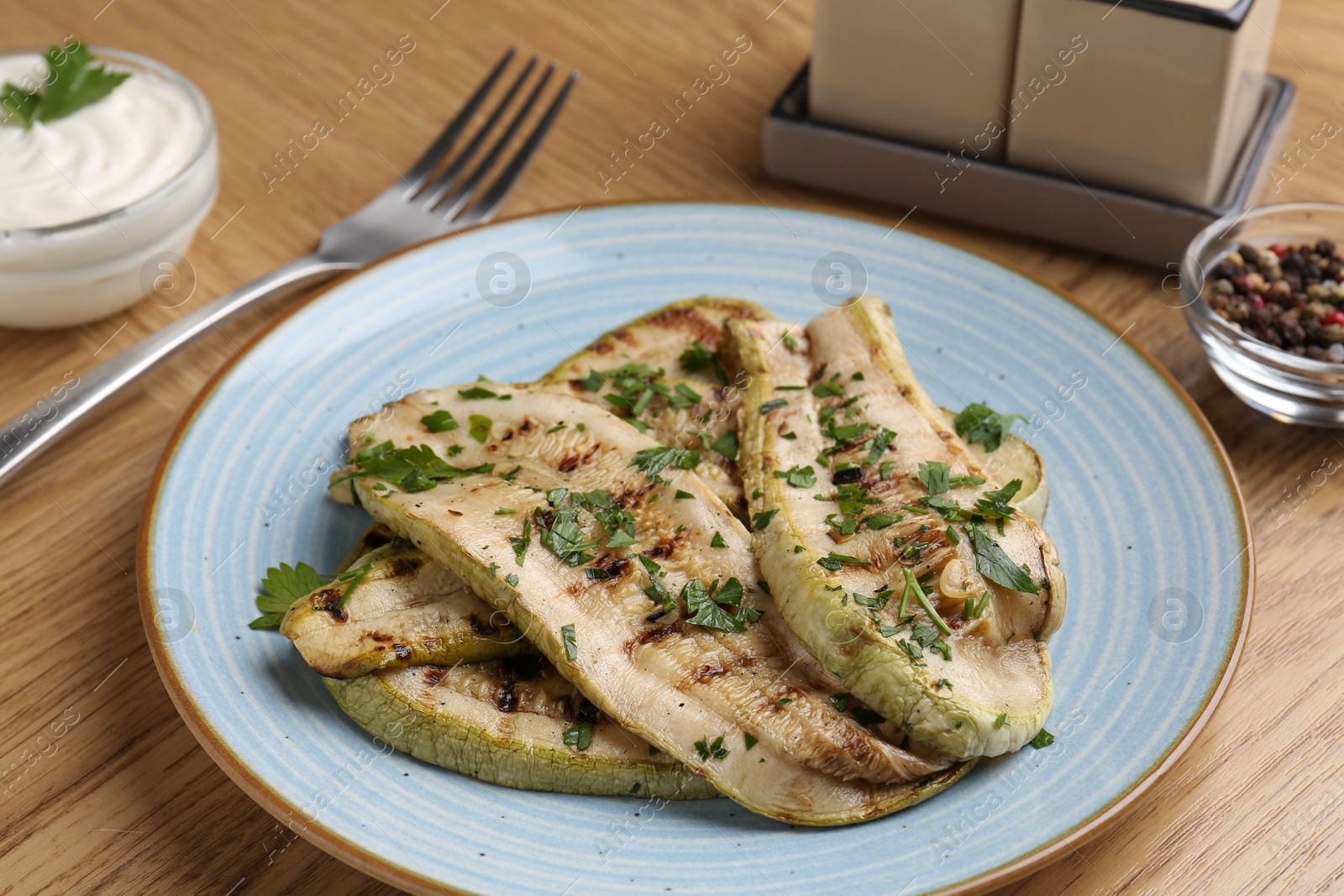 Photo of Tasty grilled courgette slices served on wooden table