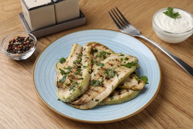 Photo of Tasty grilled courgette slices served on wooden table