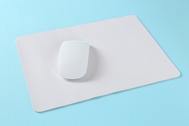 Photo of Wireless mouse and mousepad on light blue background