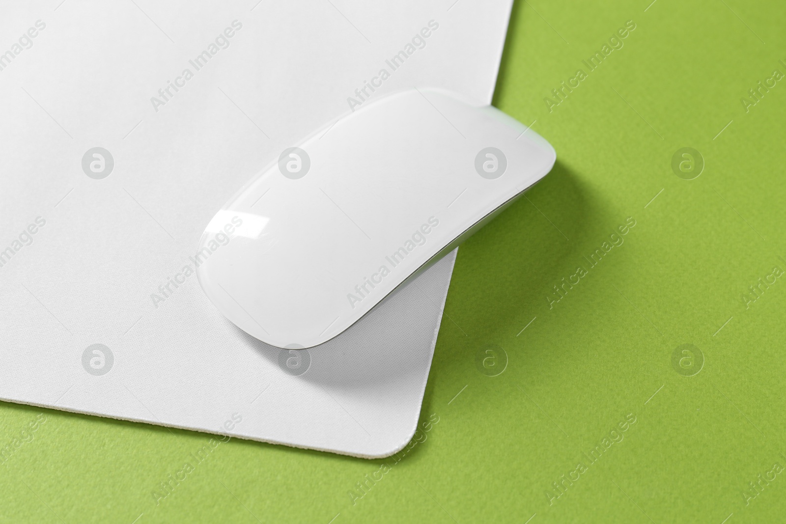 Photo of Wireless mouse and mousepad on green background, space for text