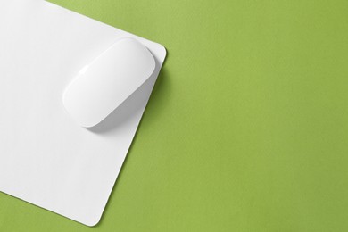 Wireless mouse and mousepad on green background, top view. Space for text