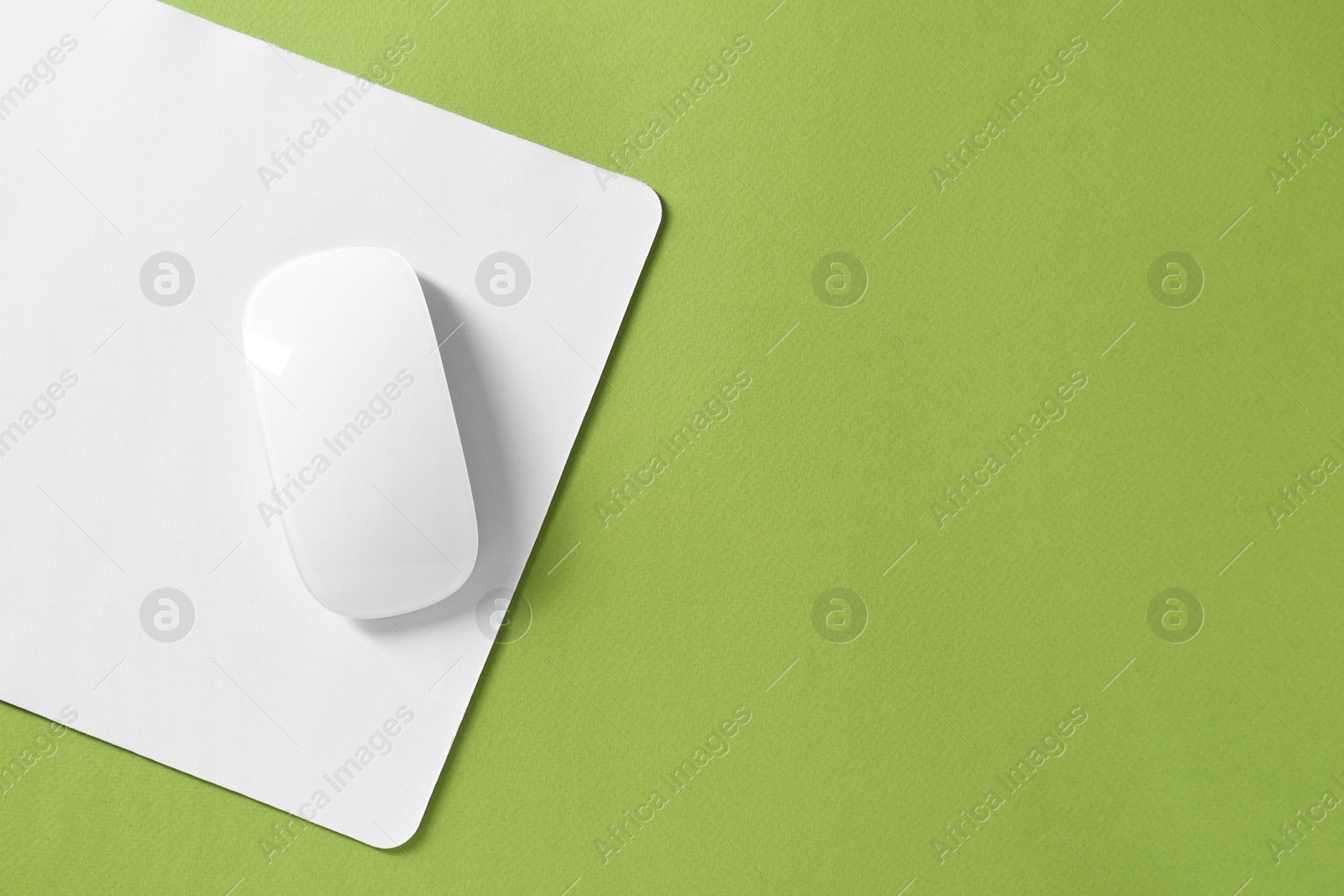 Photo of Wireless mouse and mousepad on green background, top view. Space for text