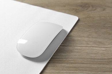 Wireless mouse and mousepad on wooden table, closeup. Space for text