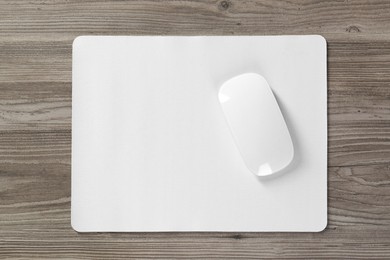 Wireless mouse and mousepad on wooden table, top view