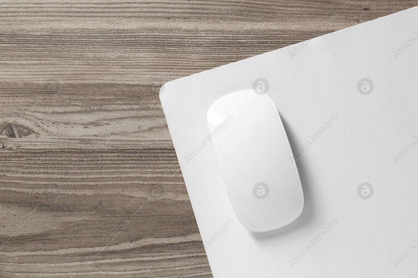 Photo of Wireless mouse and mousepad on wooden table, top view. Space for text