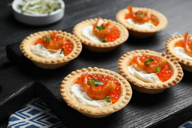 Photo of Delicious canapes with shrimps, red caviar and cream cheese on dark table, closeup