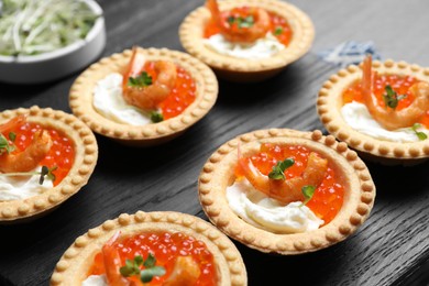 Photo of Delicious canapes with shrimps, red caviar and cream cheese on dark table, closeup