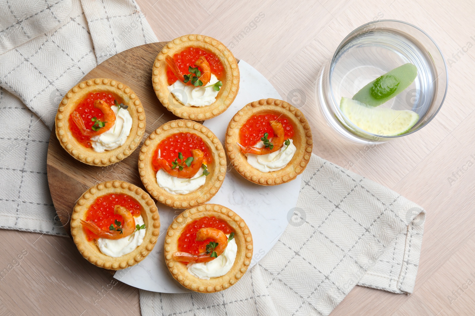 Photo of Delicious canapes with shrimps, red caviar and cream cheese served on light table, flat lay