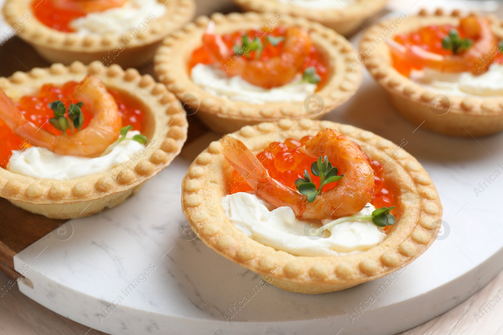 Photo of Delicious canapes with shrimps, red caviar and cream cheese on light table, closeup