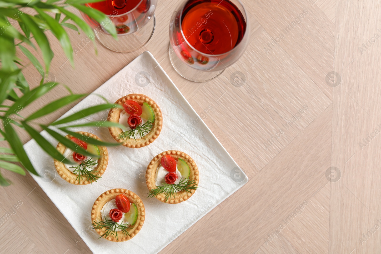 Photo of Delicious canapes with dry smoked sausages, cream cheese and vegetables served on wooden table, flat lay. Space for text