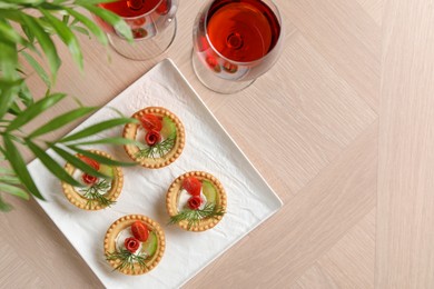 Delicious canapes with dry smoked sausages, cream cheese and vegetables served on wooden table, flat lay. Space for text