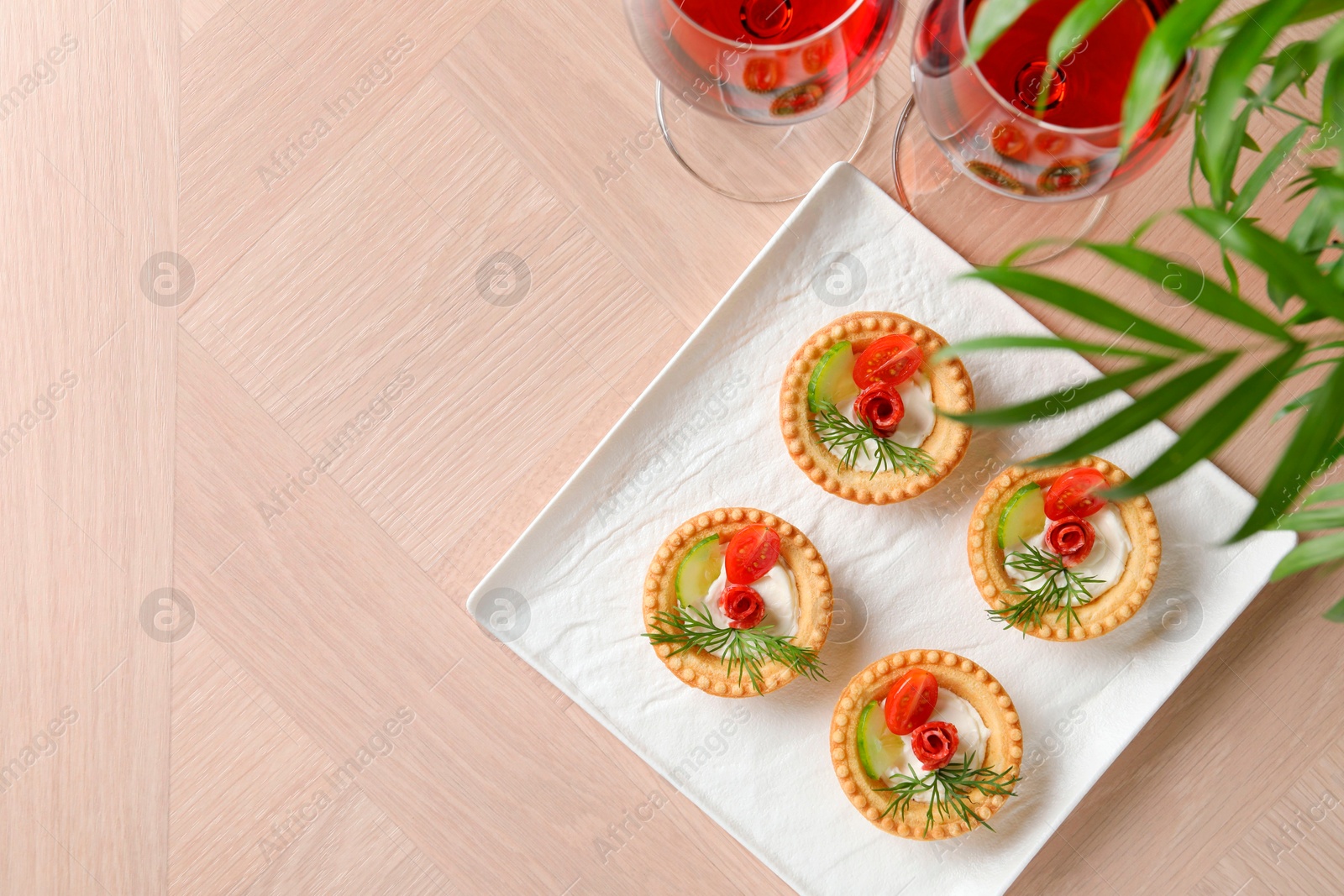 Photo of Delicious canapes with dry smoked sausages, cream cheese and vegetables served on wooden table, flat lay. Space for text