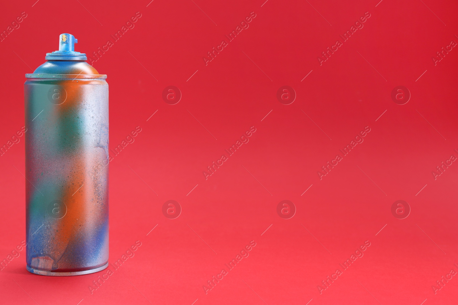 Photo of One can of bright spray paint on red background, space for text