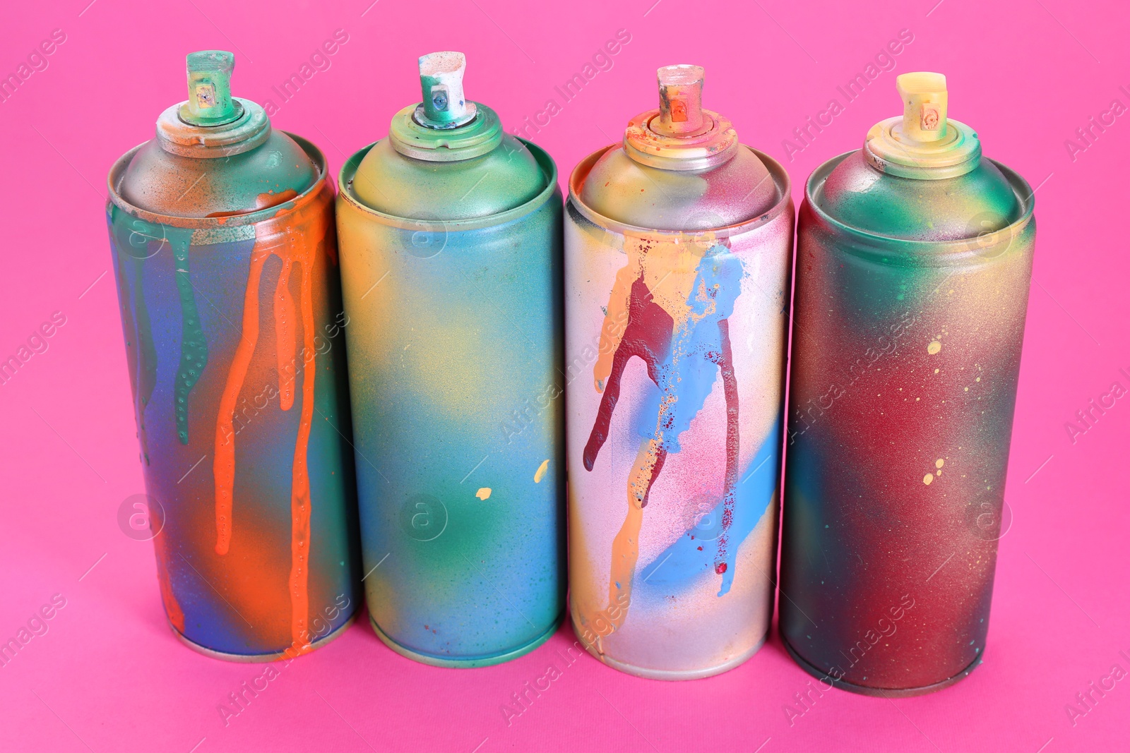 Photo of Many spray paint cans on pink background