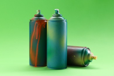 Photo of Bright spray paint cans on green background