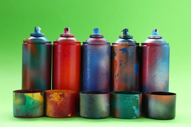 Photo of Many spray paint cans with caps on green background