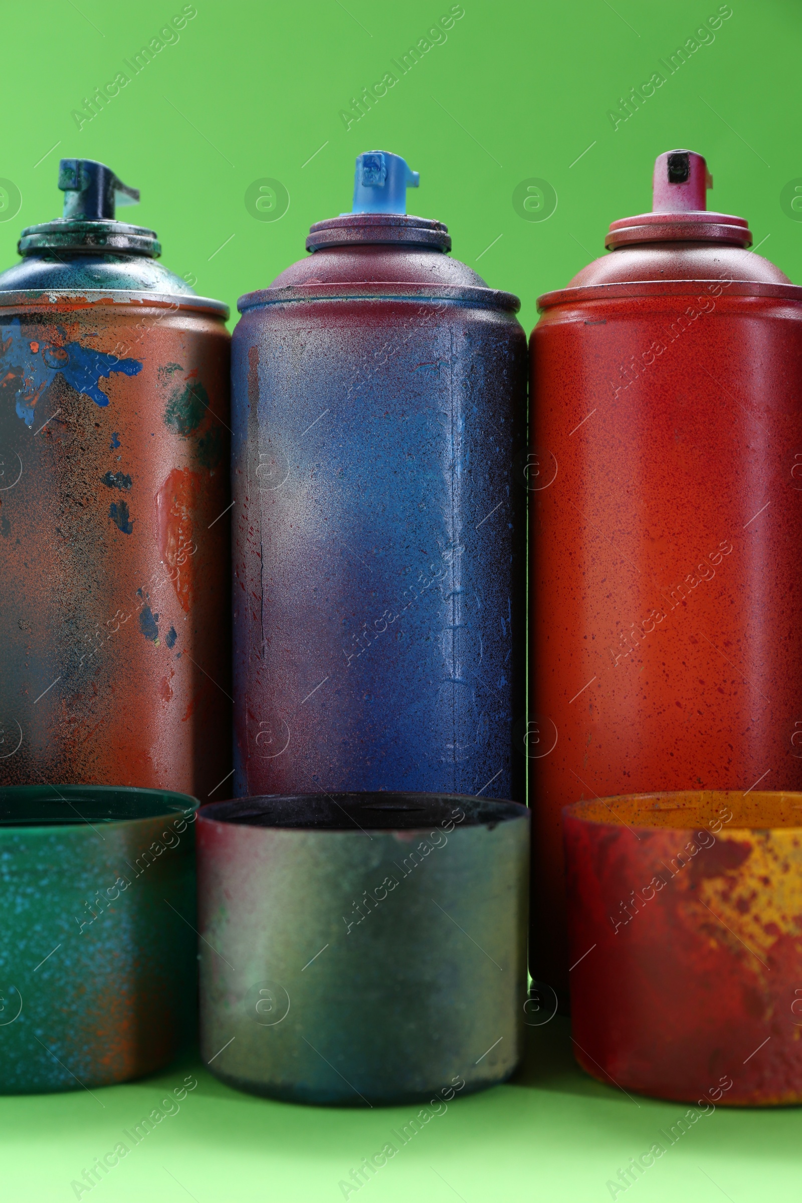 Photo of Many spray paint cans with caps on green background