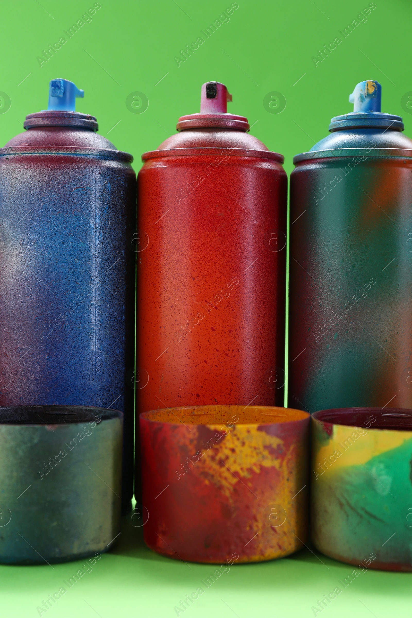 Photo of Many spray paint cans with caps on green background