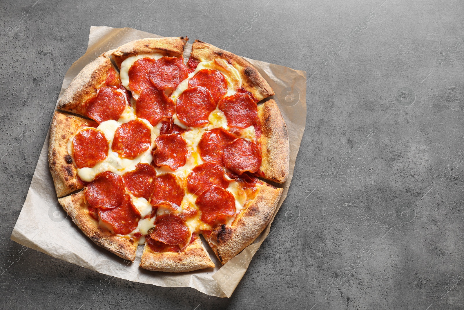 Photo of Tasty pepperoni pizza on grey table, top view. Space for text