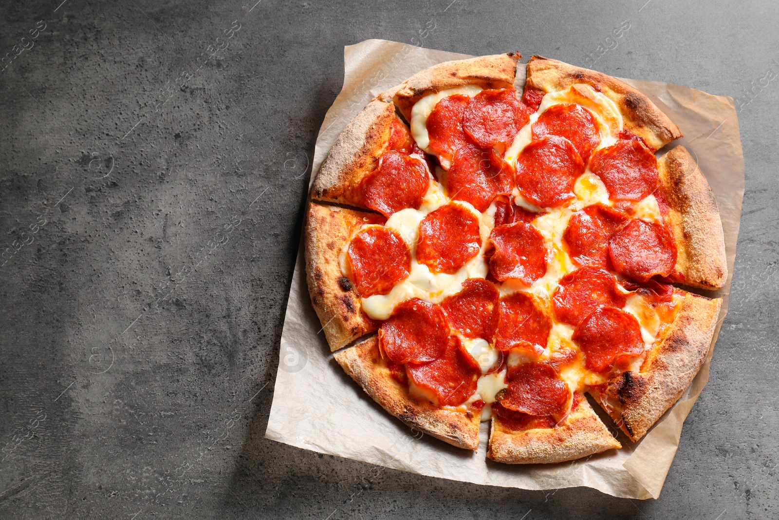 Photo of Tasty pepperoni pizza on grey table, top view. Space for text