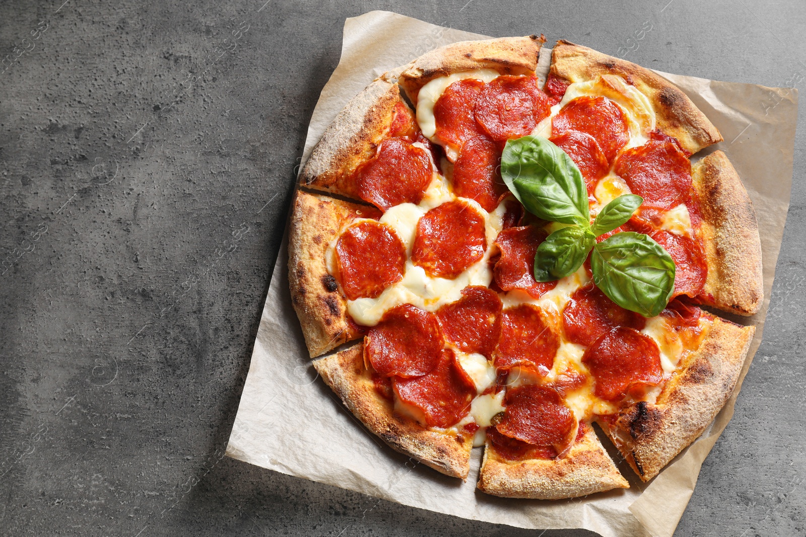 Photo of Tasty pepperoni pizza with basil on grey table, top view. Space for text