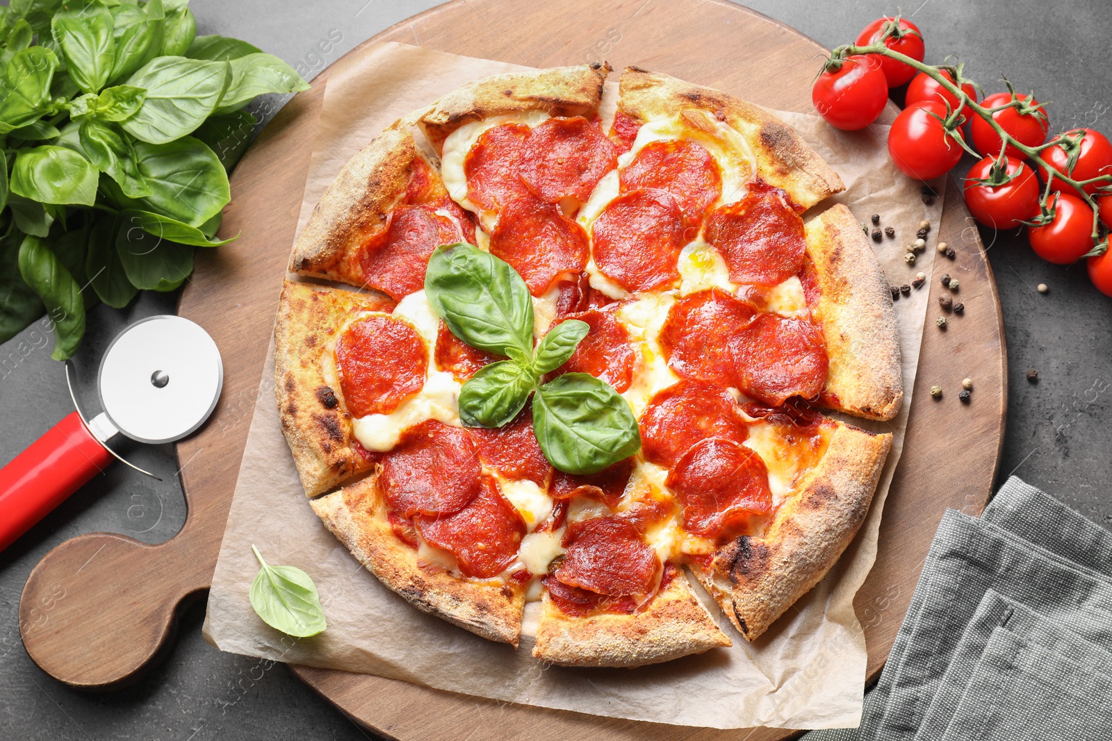 Photo of Tasty pepperoni pizza, cutter and ingredients on grey table, top view