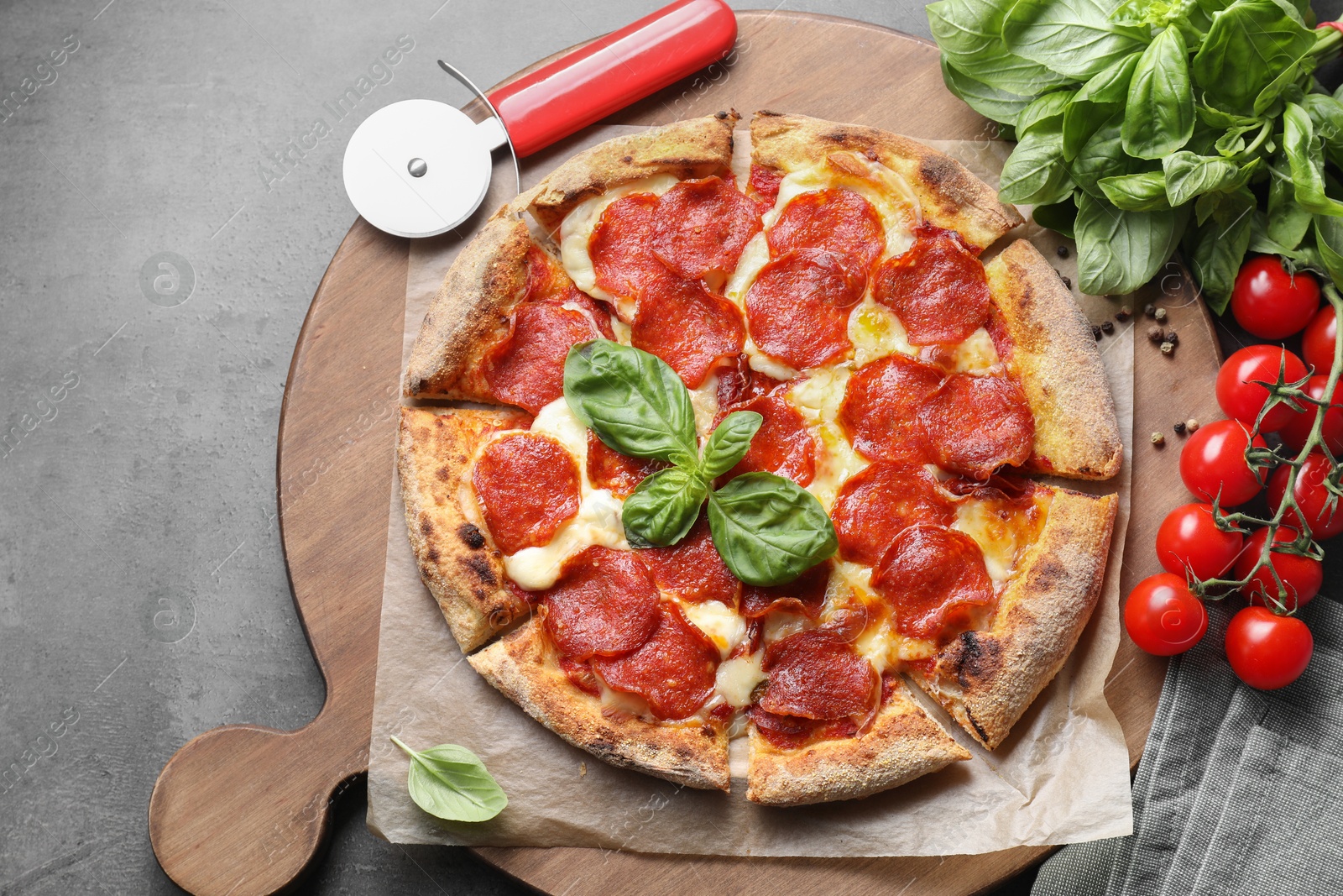 Photo of Tasty pepperoni pizza, cutter and ingredients on grey table, top view