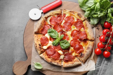 Photo of Tasty pepperoni pizza, cutter and ingredients on grey table, top view