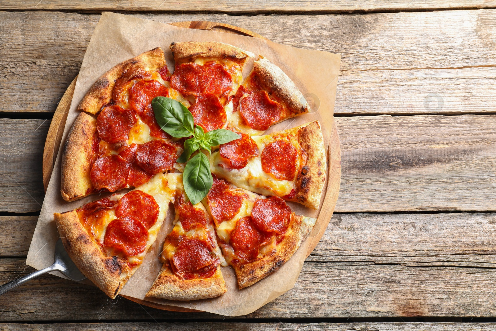 Photo of Tasty pepperoni pizza with basil on wooden table, top view. Space for text