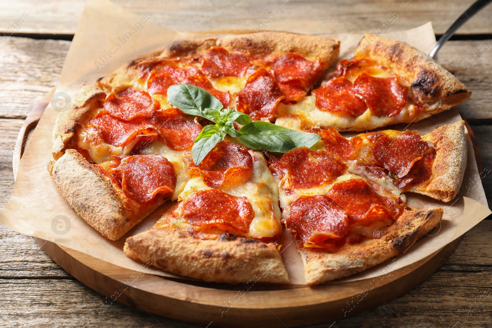 Photo of Tasty pepperoni pizza with basil on wooden table