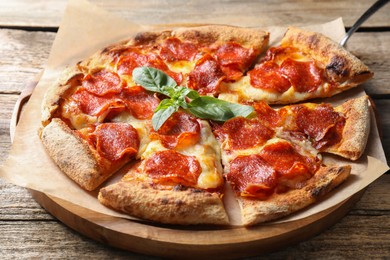 Photo of Tasty pepperoni pizza with basil on wooden table