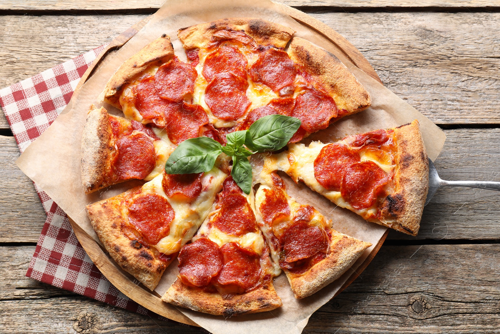 Photo of Tasty pepperoni pizza with basil on wooden table, top view