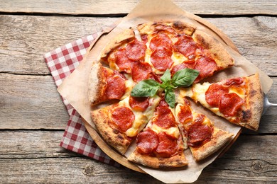 Photo of Tasty pepperoni pizza with basil on wooden table, top view