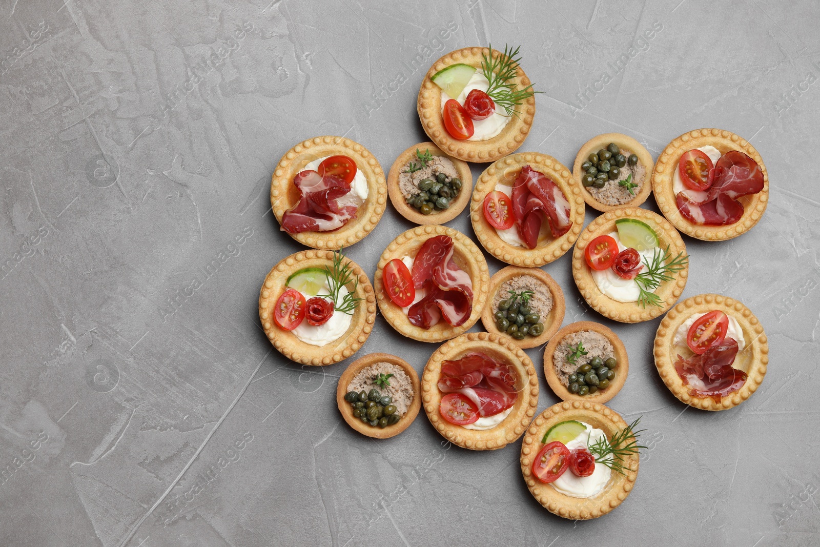 Photo of Different delicious canapes on grey textured table, flat lay