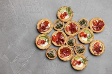 Different delicious canapes on grey textured table, flat lay