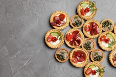 Different delicious canapes on grey textured table, flat lay. Space for text