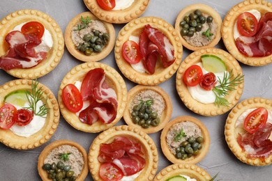 Photo of Different delicious canapes on grey textured table, flat lay