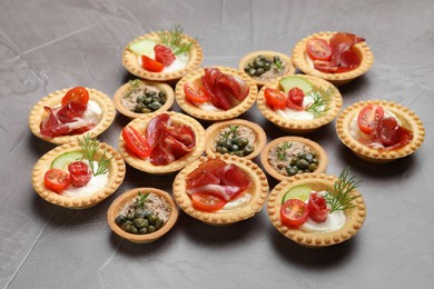 Different delicious canapes on grey textured table