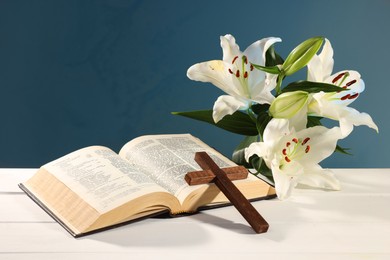 Photo of Wooden cross, Bible and beautiful lily flowers on white table against dark background. Religion of Christianity